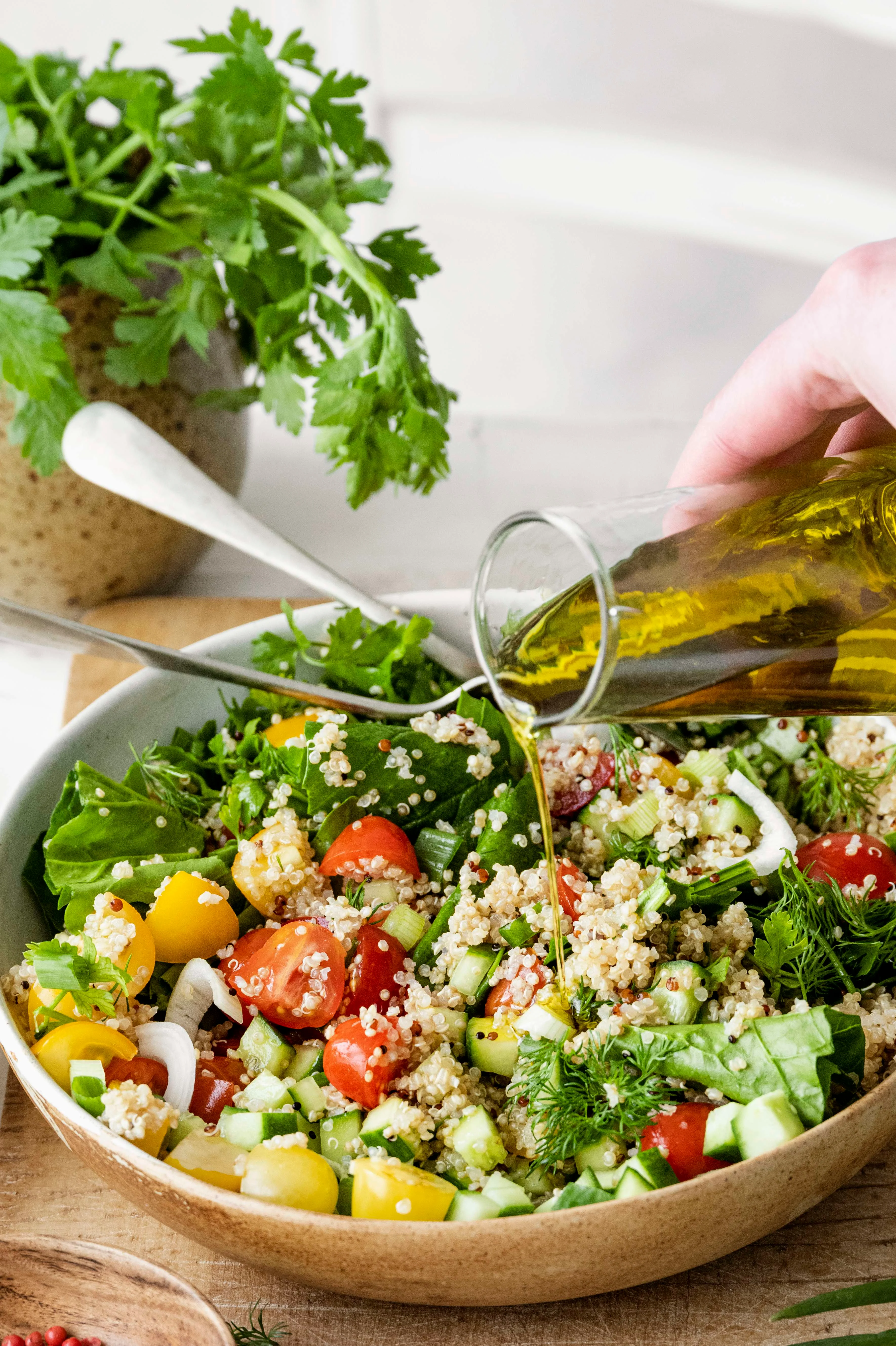 Olive oil being poured over a vegan mediterranean salad.
