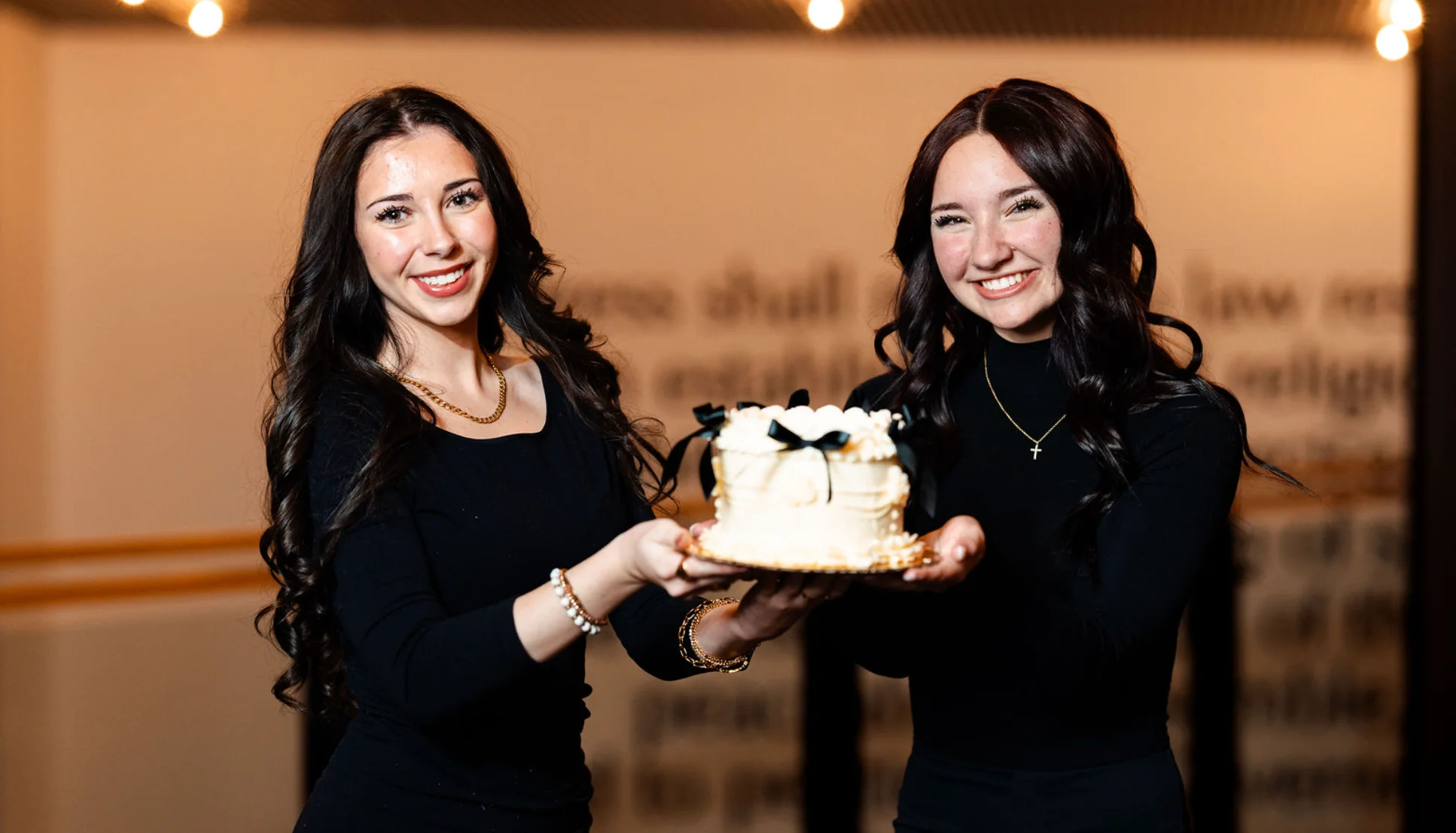 Two women celebrating with a decorated cake in a festive setting