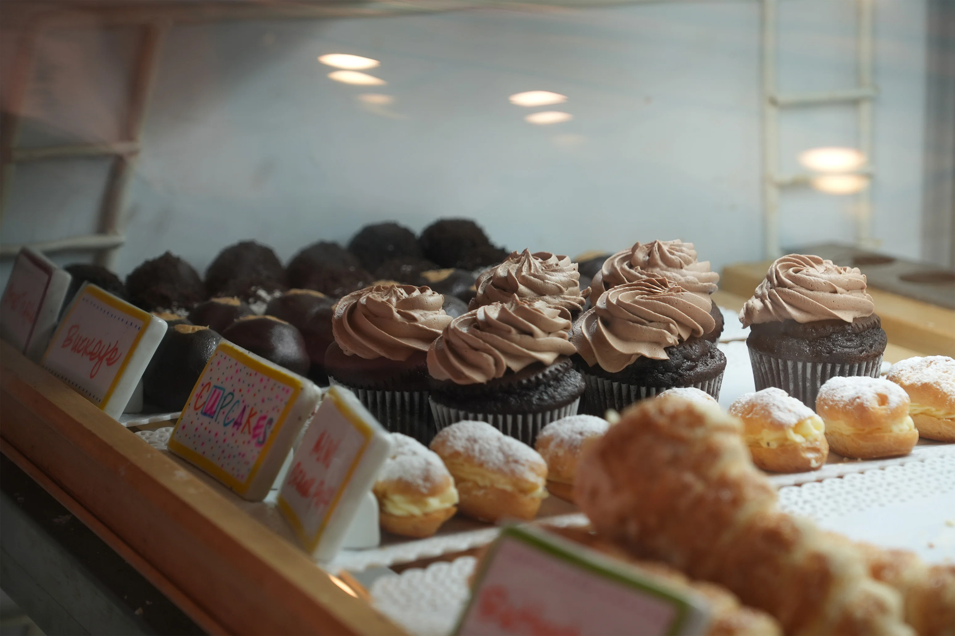 Bakery display of chocolate cupcakes and cream-filled pastries
