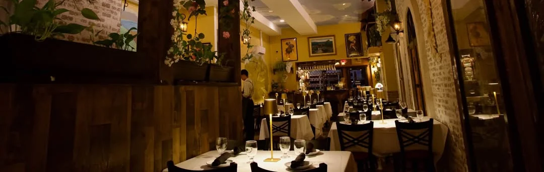 Elegant restaurant dining room with hanging greenery, warm lighting, and white tablecloths