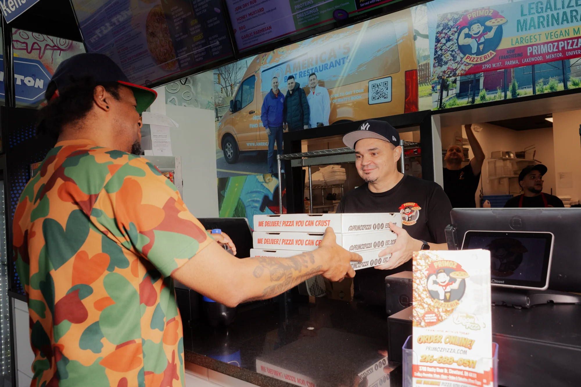 Customer receiving pizza boxes at a vibrant restaurant counter