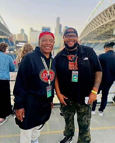 Two men posing at a stadium event with city skyline in background