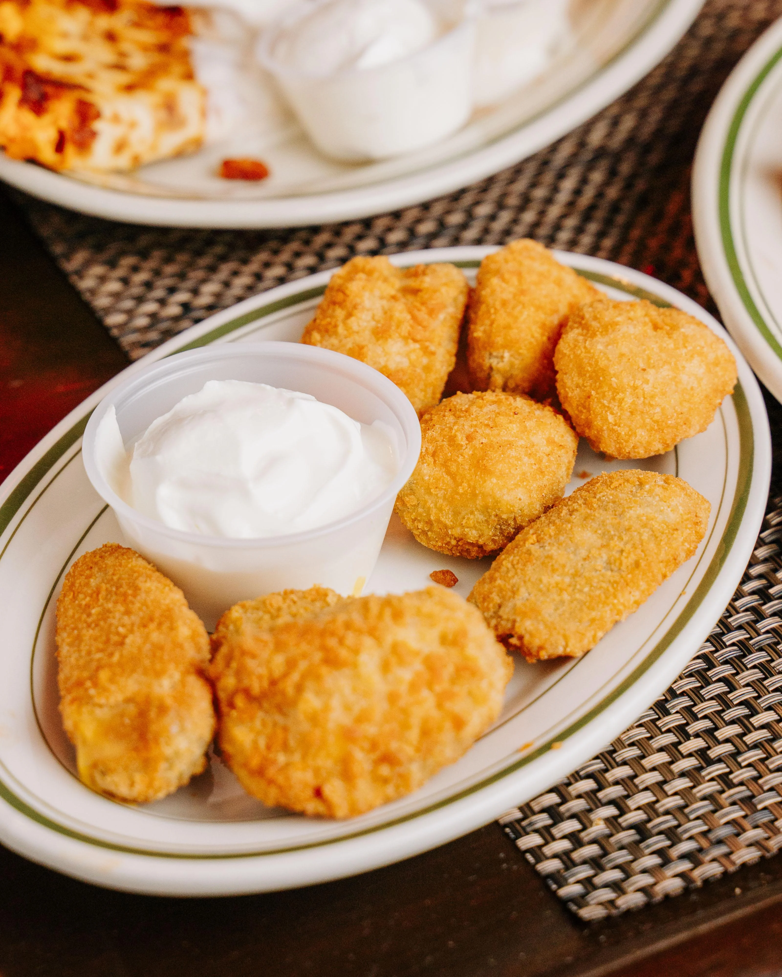 A plate of assorted fried snacks including golden nuggets and a side of white dipping sauce.