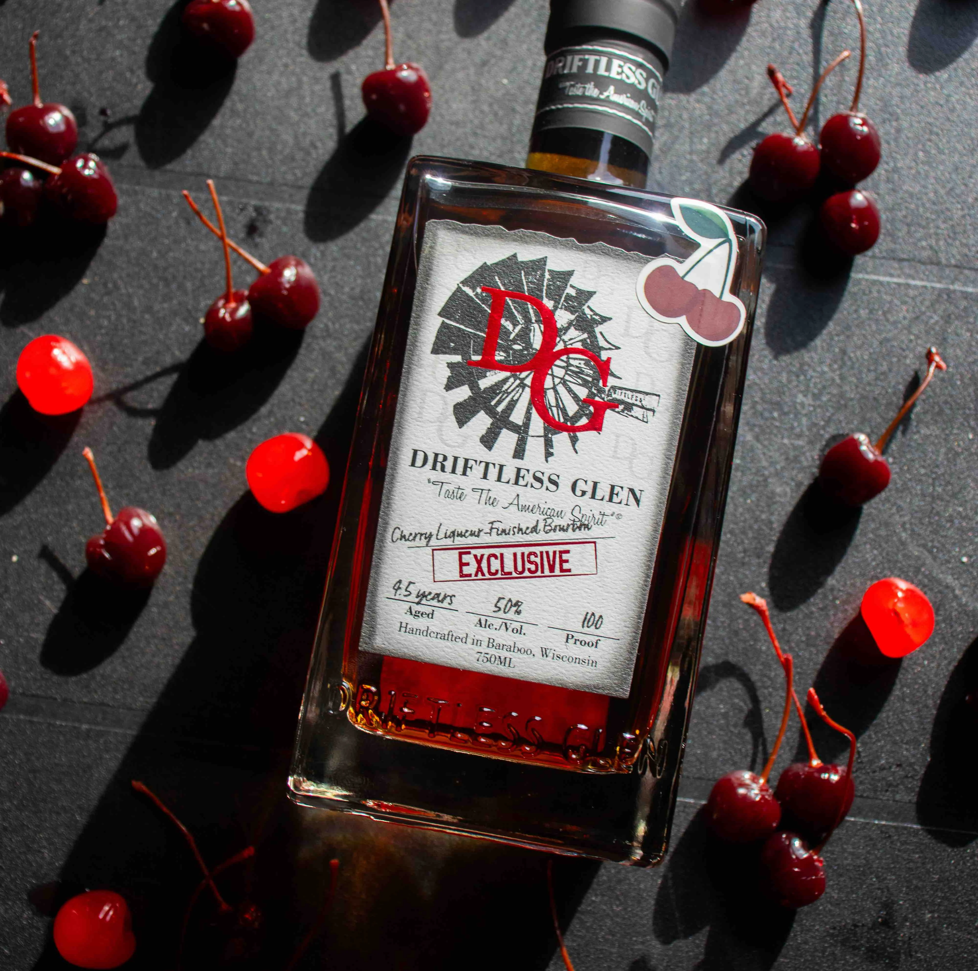 A bottle of Vanilla-Finished Bourbon sit on a whiskey barrel with cinnamon sticks and winter dessert around it.
