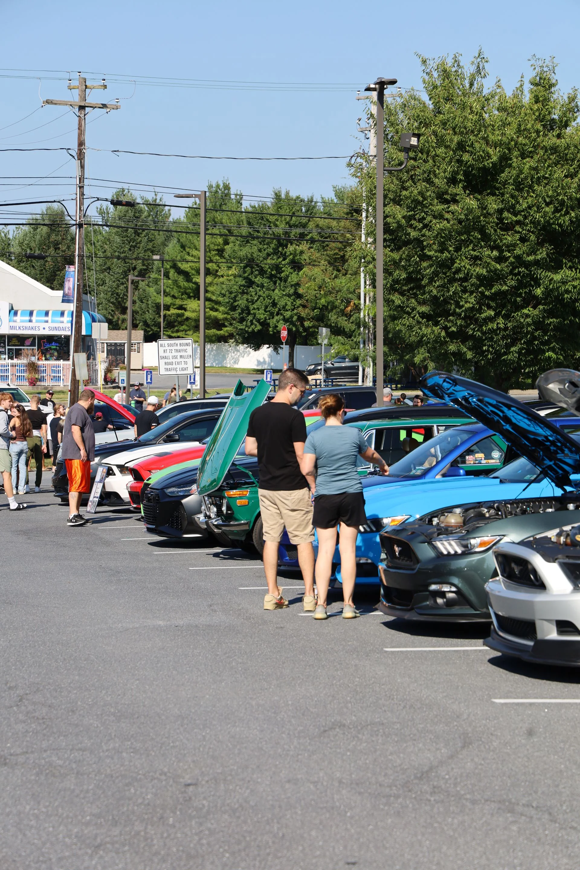 Car enthusiasts exploring a car show with various vehicles on display