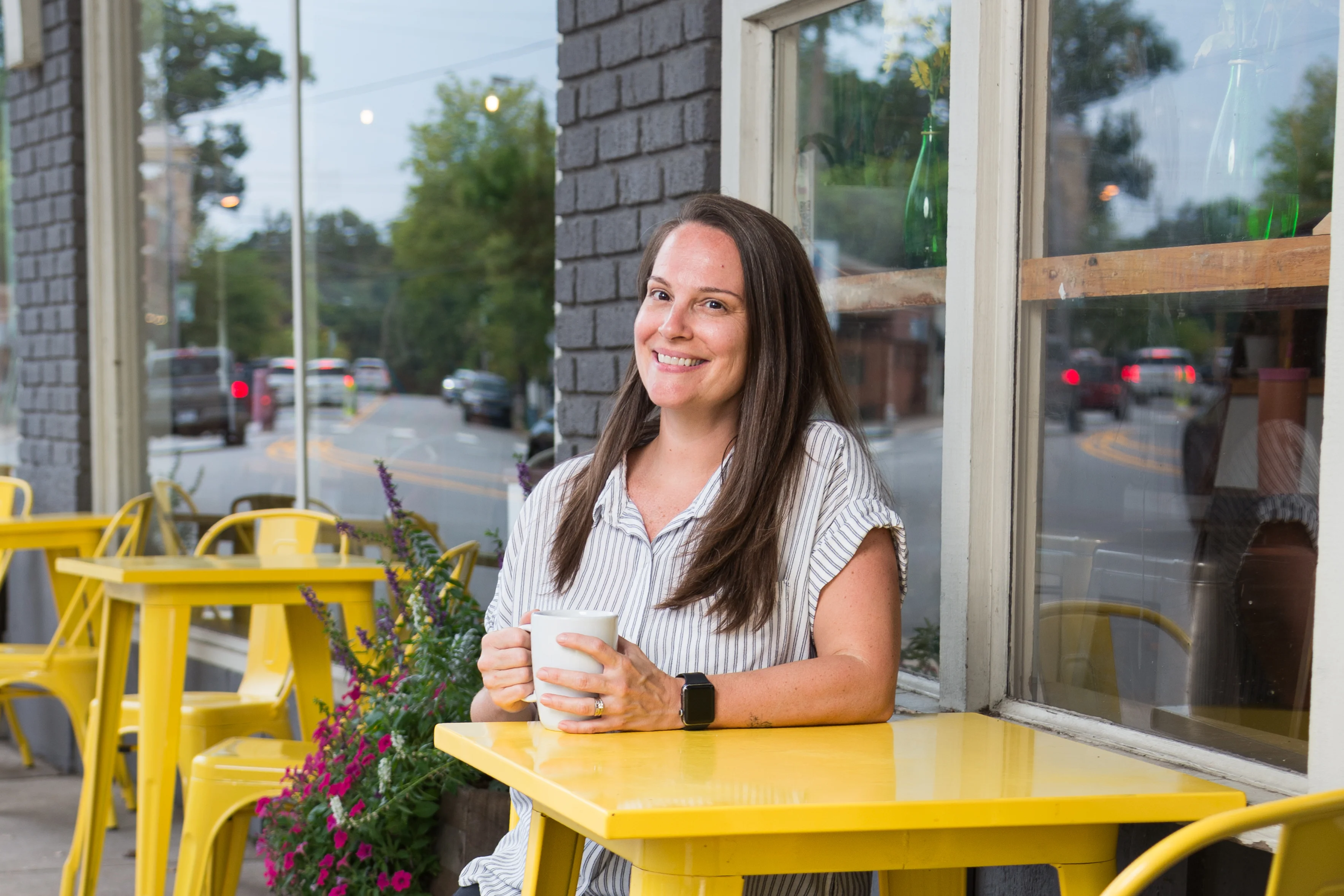 Smiling woman enjoying coffee at a bright café table
