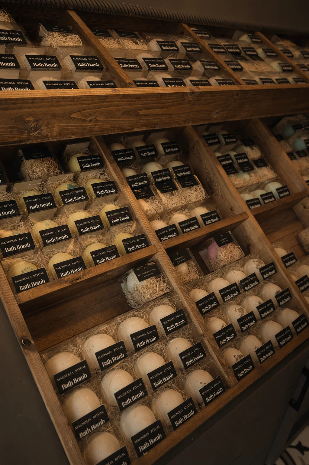Row of labeled glass bottles on a wooden shelf in a restaurant.