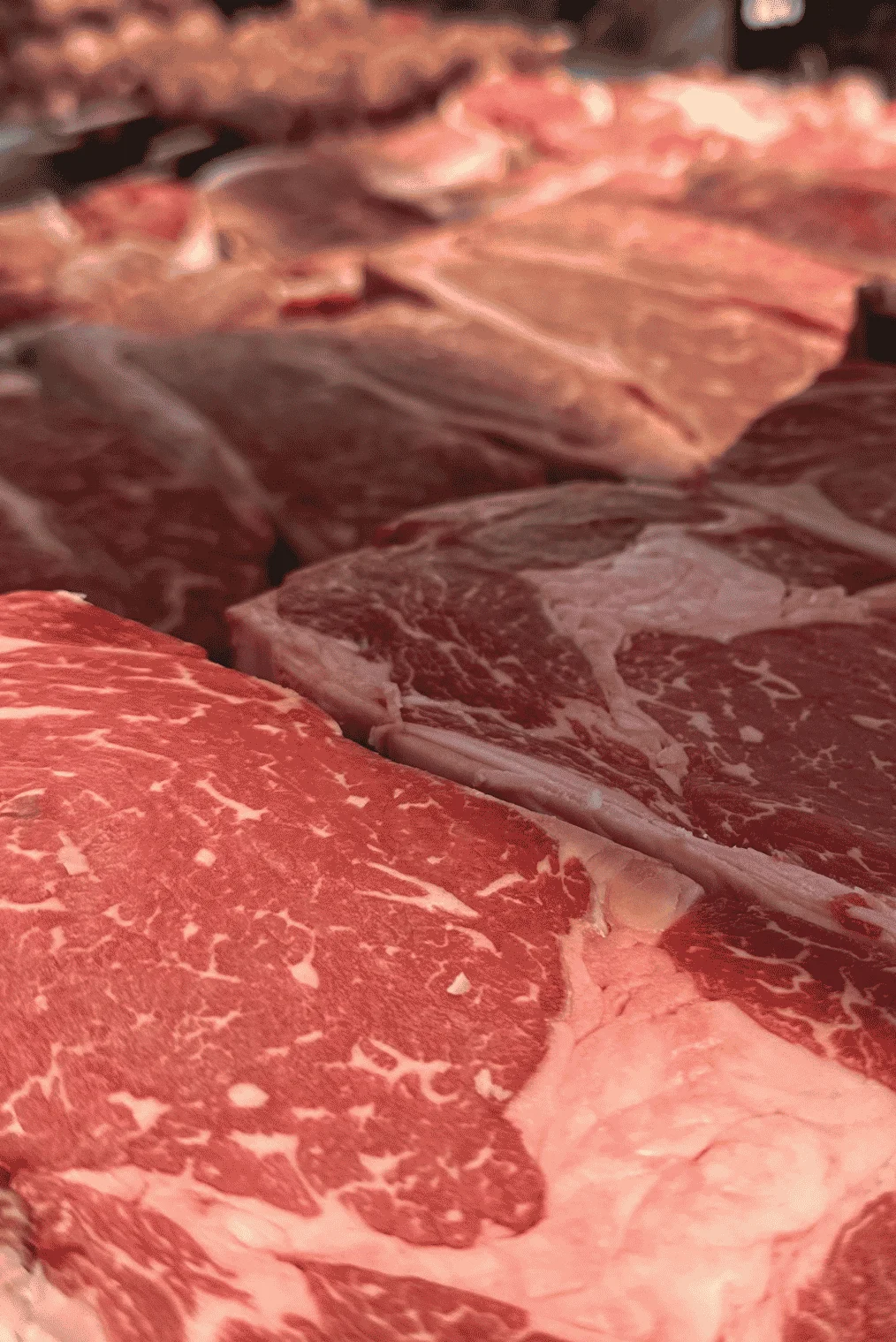 Variety of fresh cuts of beef displayed at a market.