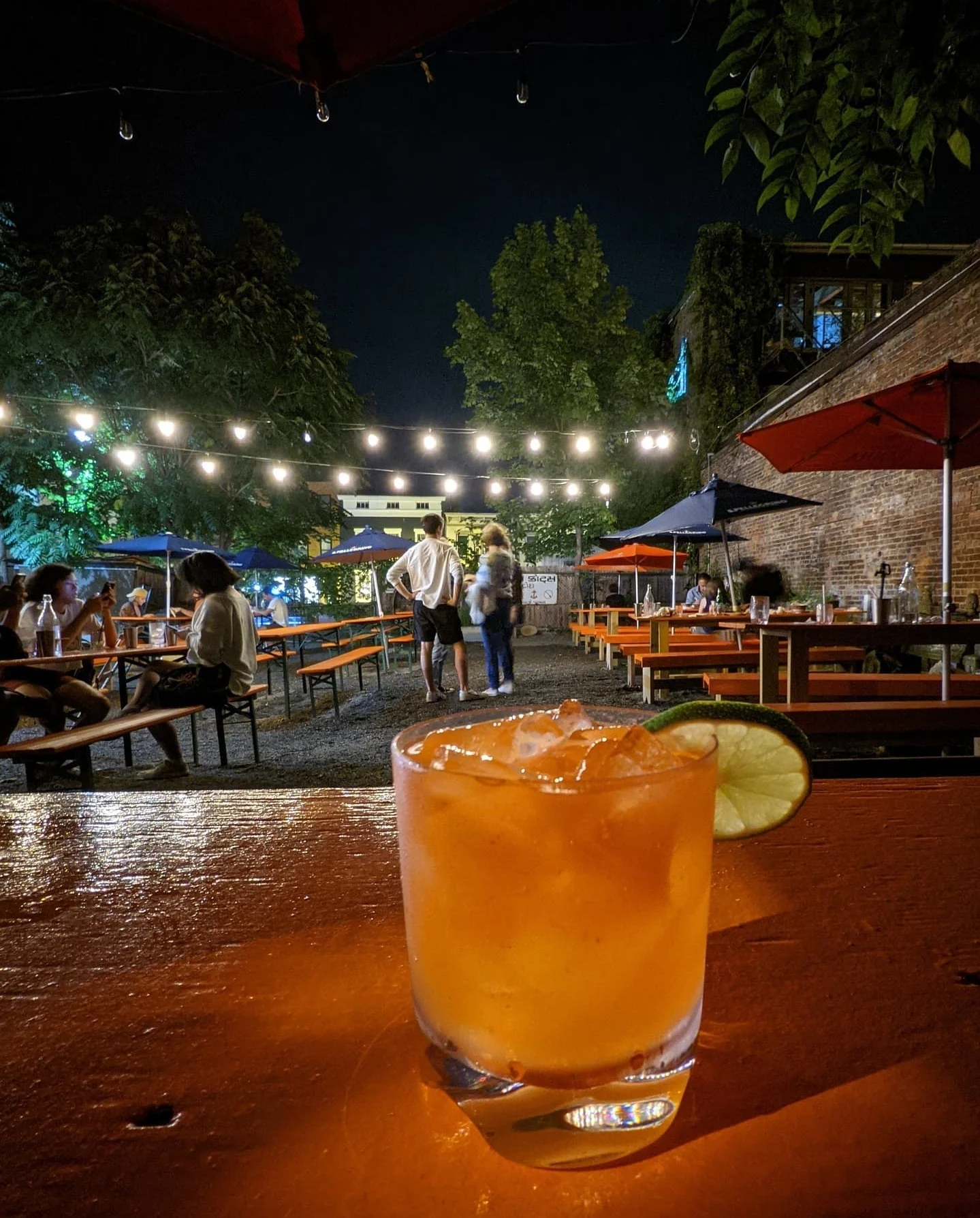 Colorful cocktail on a wooden table in a lively outdoor bar setting