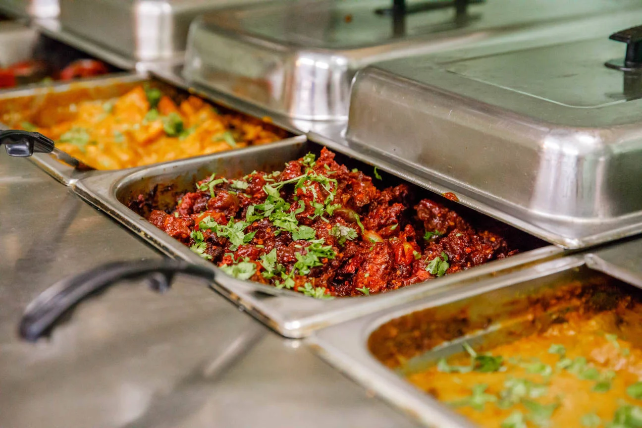 A close-up view of the fresh and vibrant buffet at Mint Indian Restaurant in Denver, showcasing a variety of authentic Indian dishes in warmers.