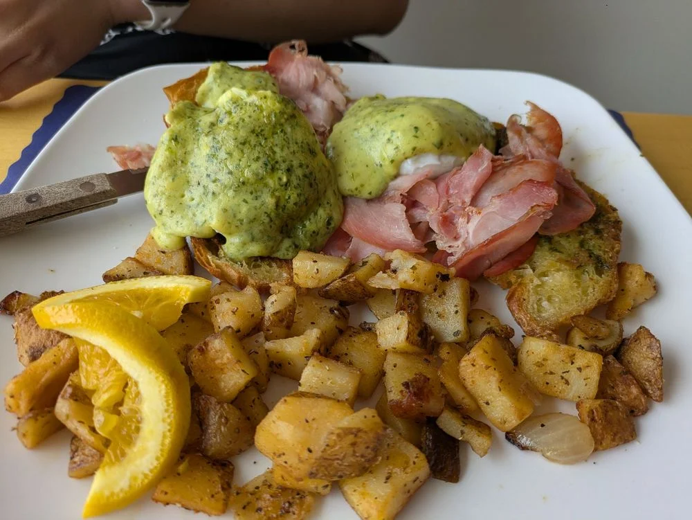 Italian Benedict with poached eggs, hollandaise sauce, and herbs on a plate.