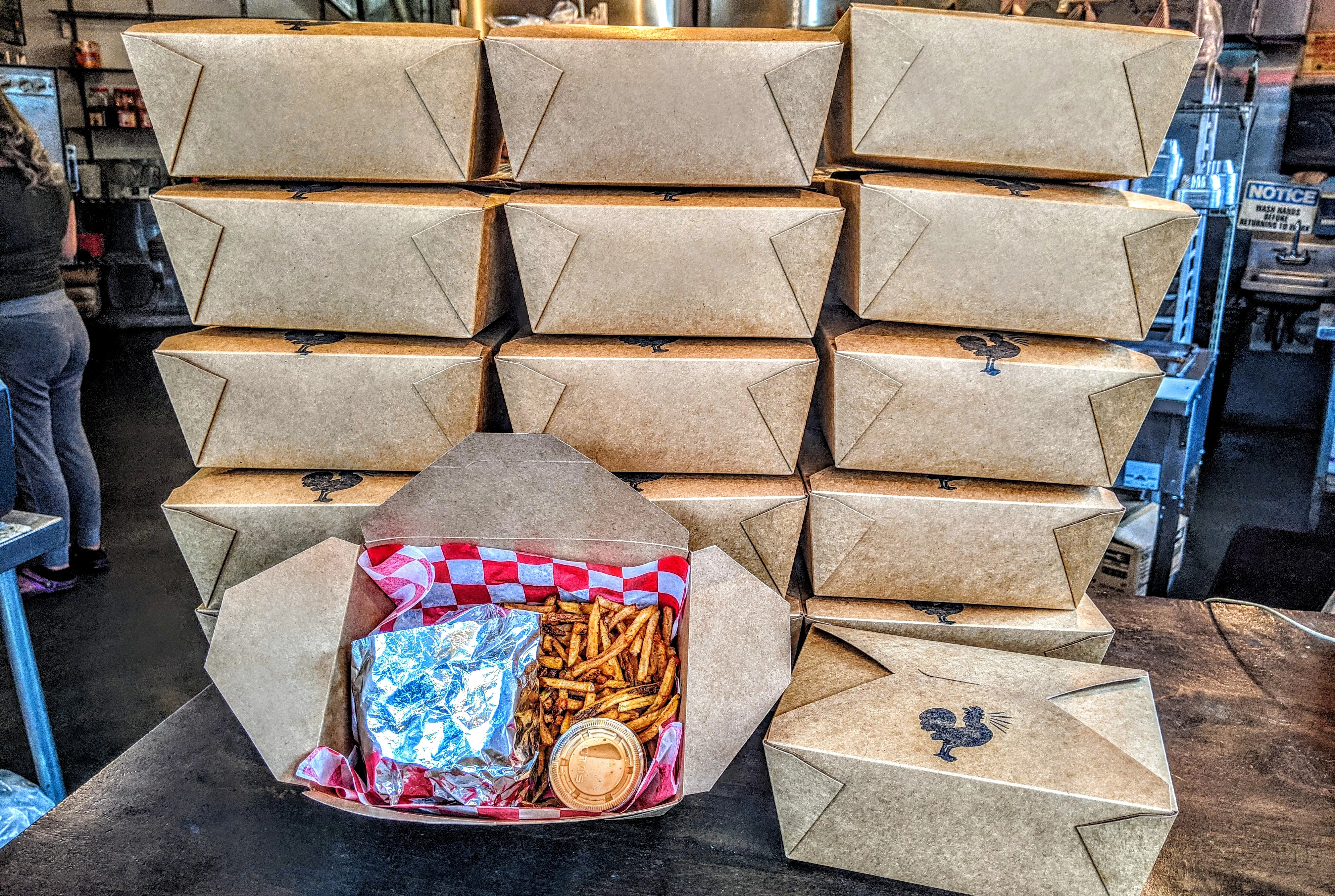 Takeout boxes stacked with fries and a wrapped sandwich