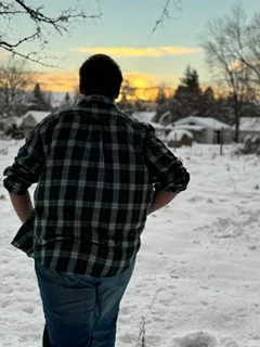 Person walking through snowy landscape at sunset