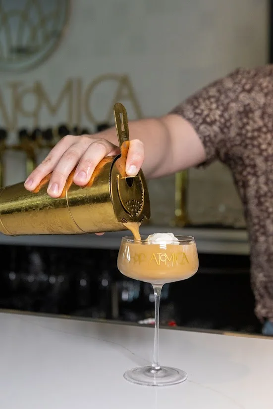 Bartender pouring a cocktail into a glass at a stylish bar
