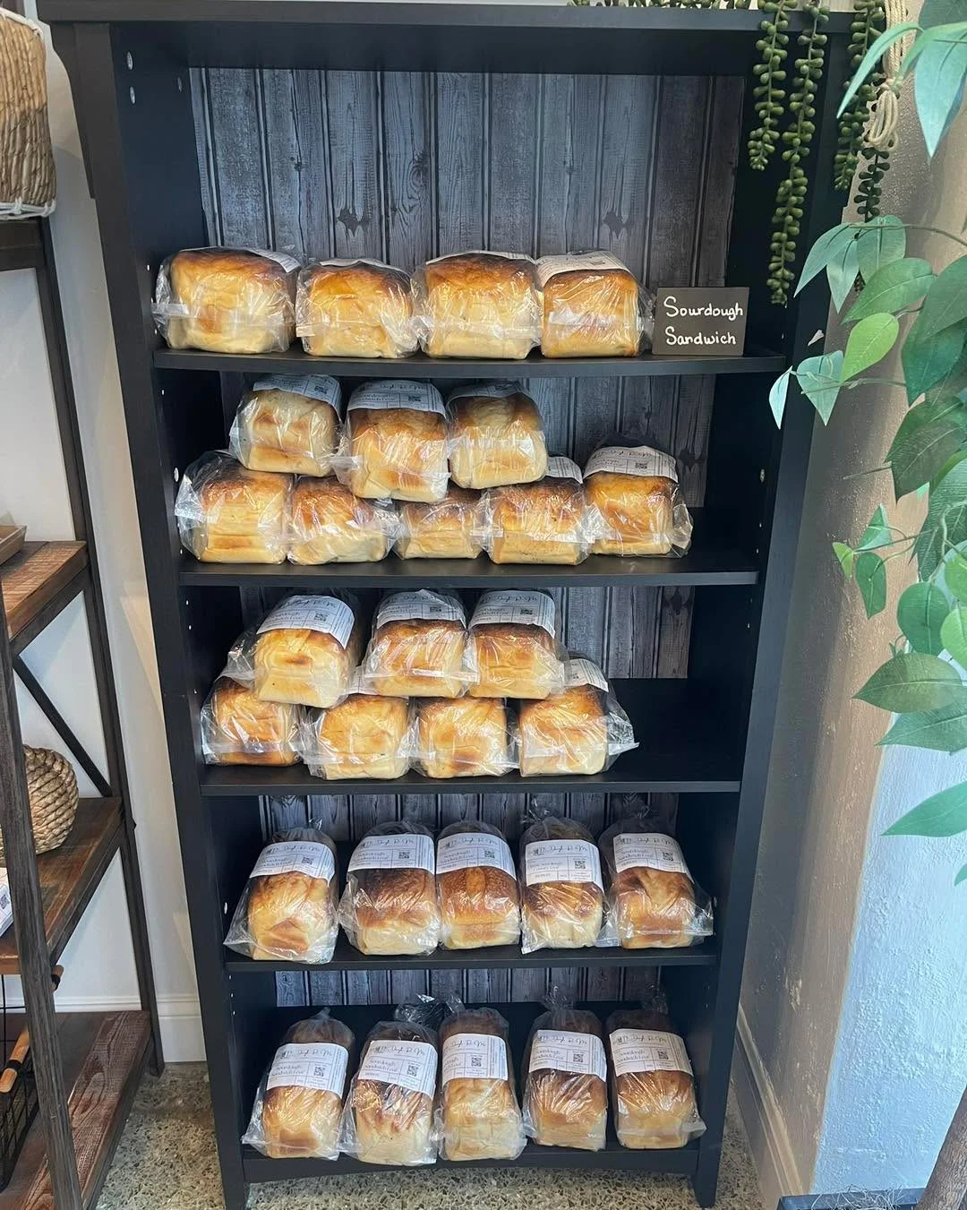 A neatly organized shelf displaying packages of sourdough sandwich loaves, showcasing freshness and variety.
