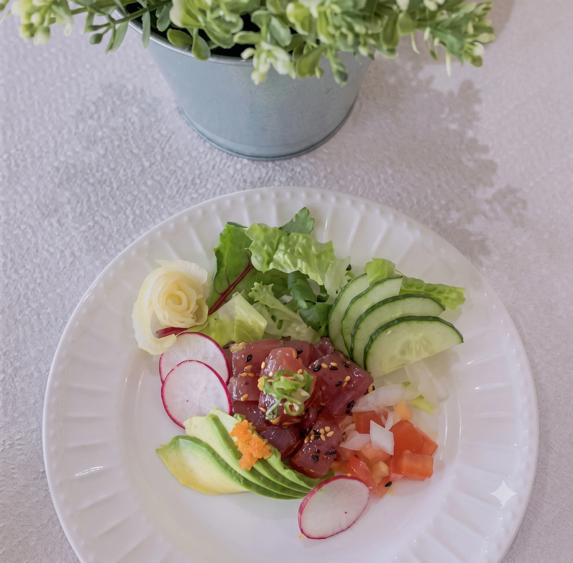 A plate of fresh sashimi with vegetables and a decorative flower garnish.