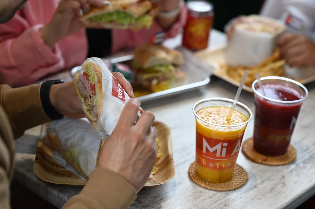 Rewards Mi Apá, customers eating sandwich mango juice