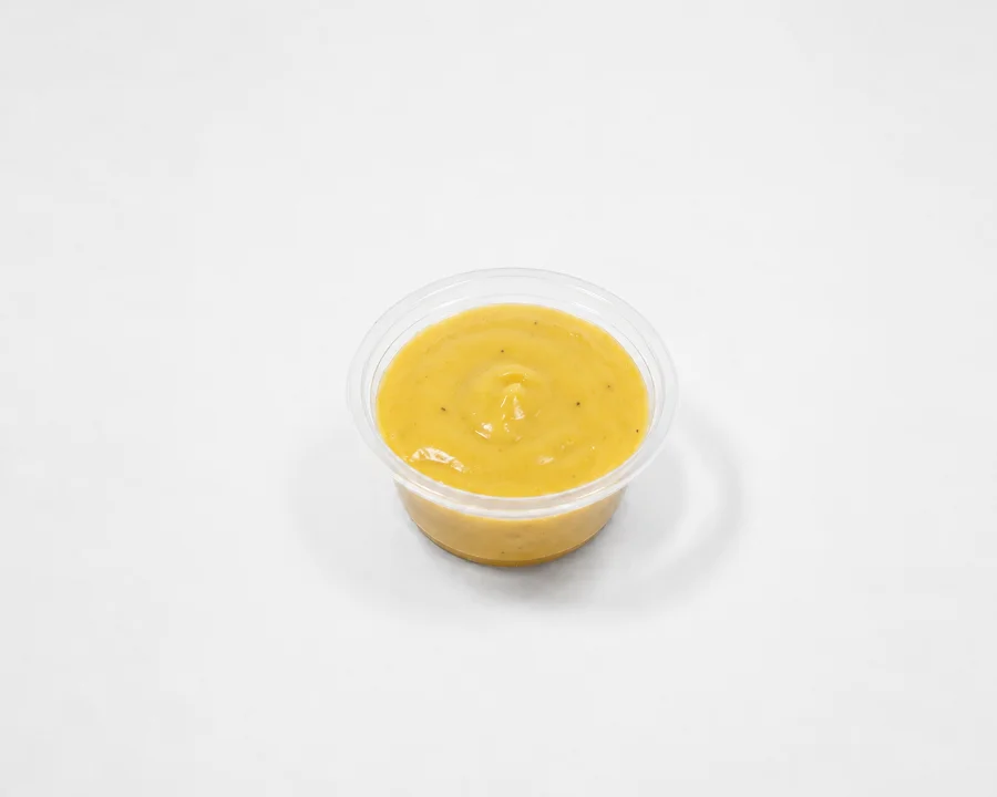 A small container of a thick, mustard-colored sauce, likely sweet or savory.