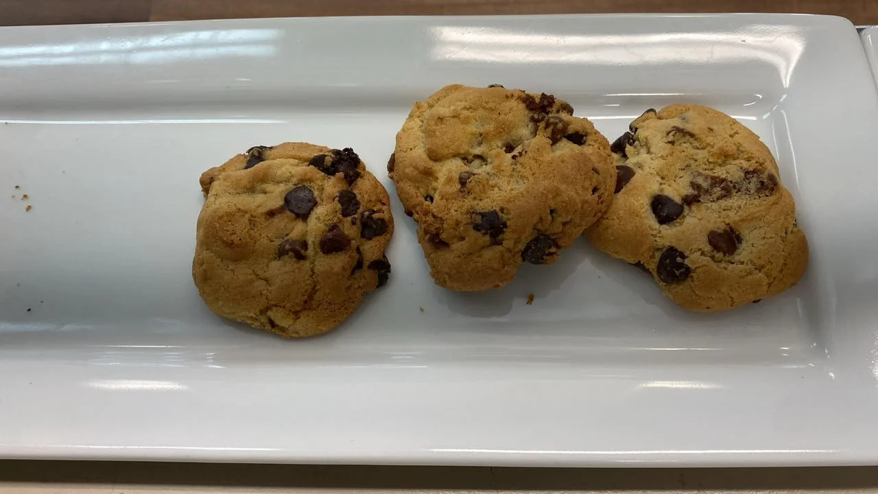 A plate of three chocolate chip cookies, featuring a crumbly texture and chocolate morsels.