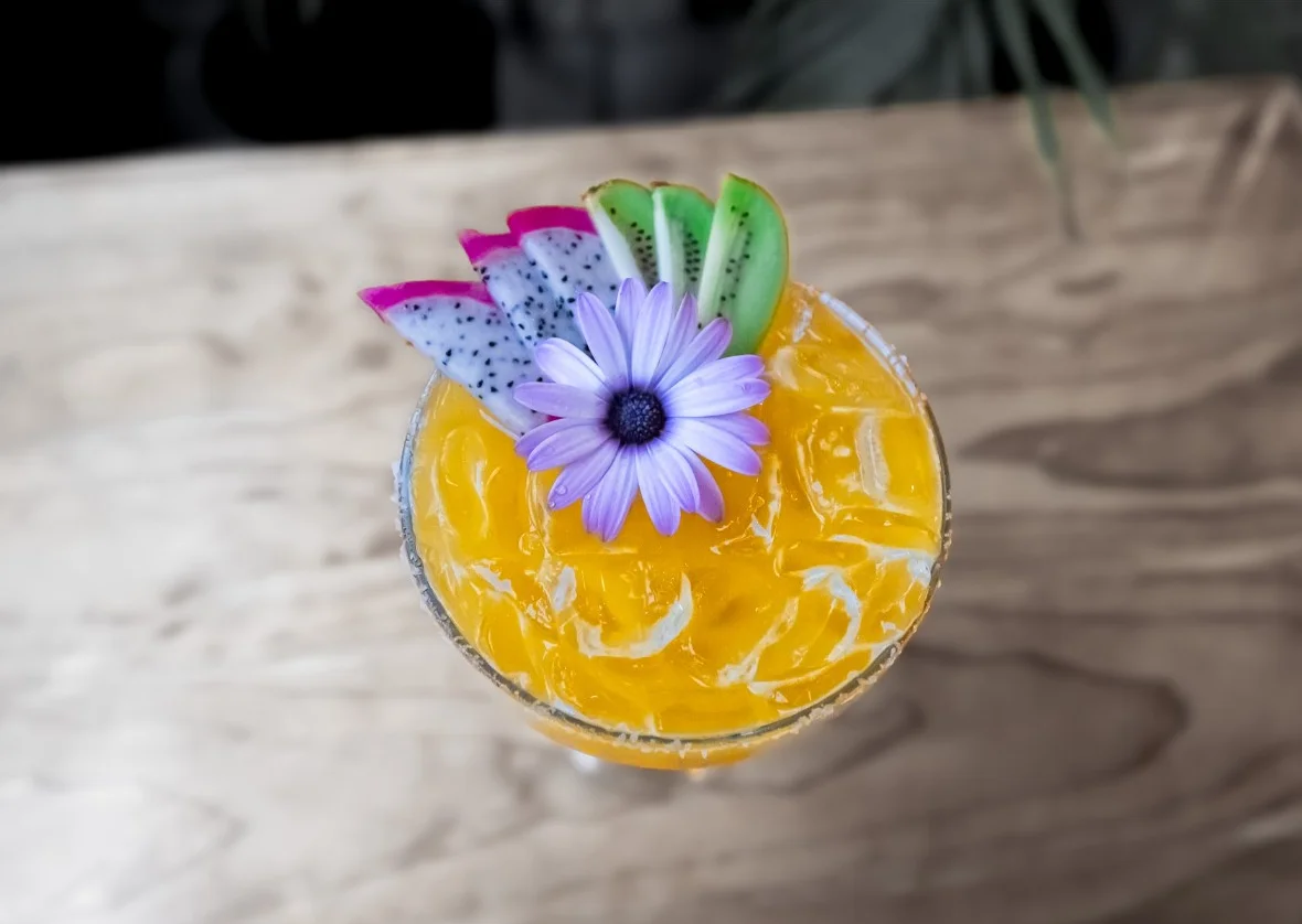 Vibrant tropical cocktail garnished with fruit and a flower
