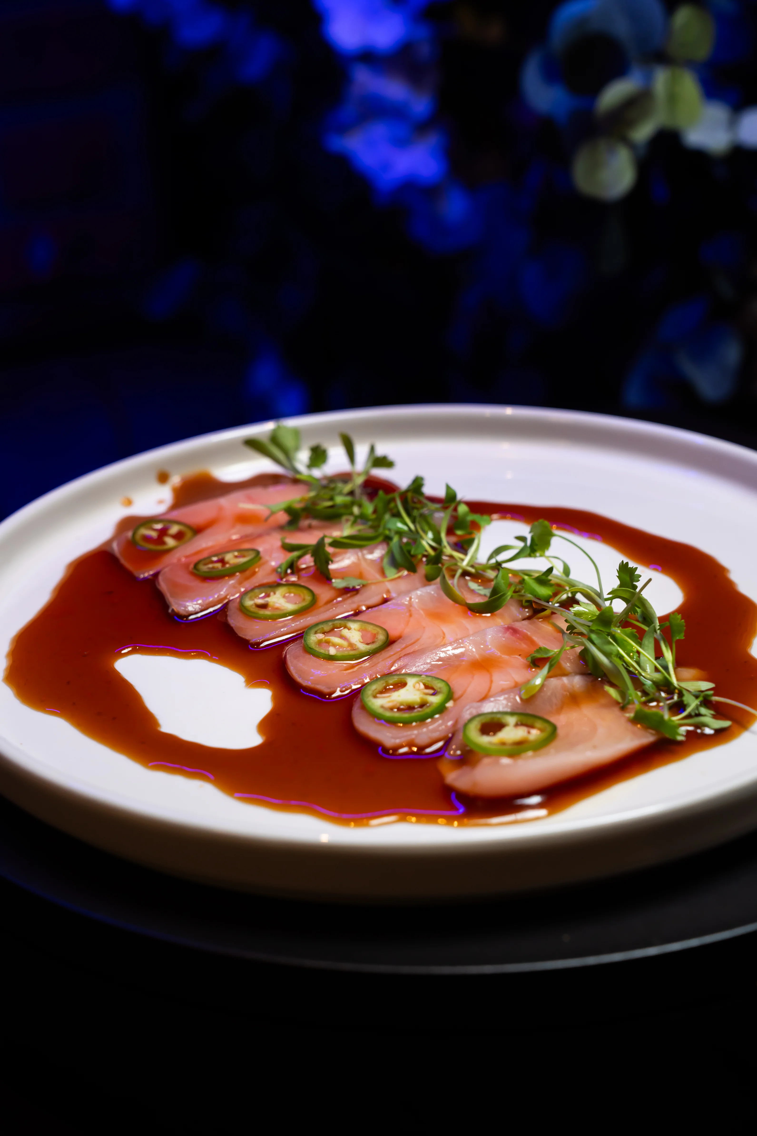 Japanese sashimi with jalapeño and herbs on a white plate