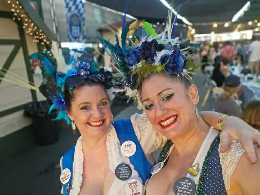 Two women in festive attire at a lively outdoor event