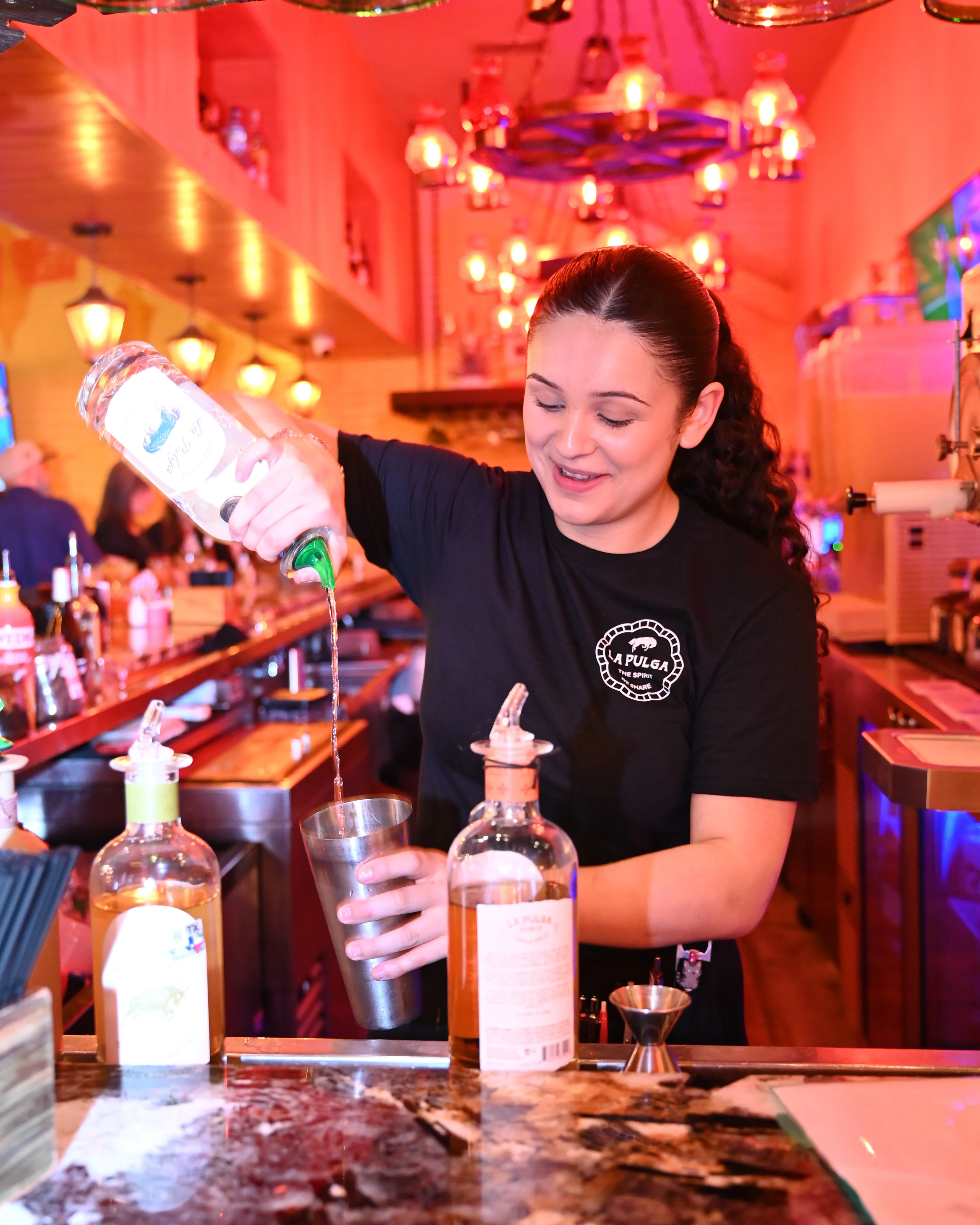 Bartender pouring a cocktail at a vibrant bar