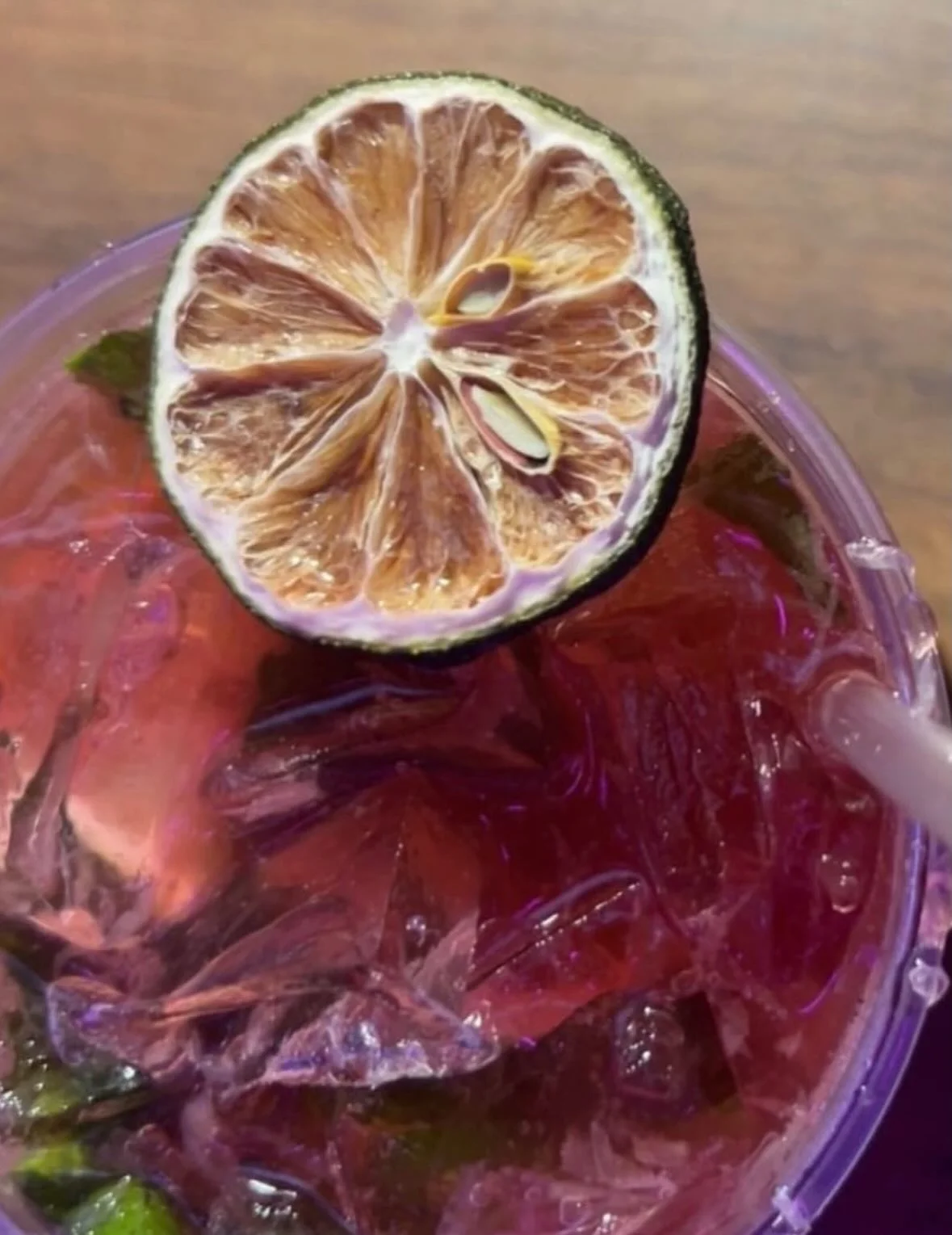 A close-up of a drink with ice and a dried lime slice on top.