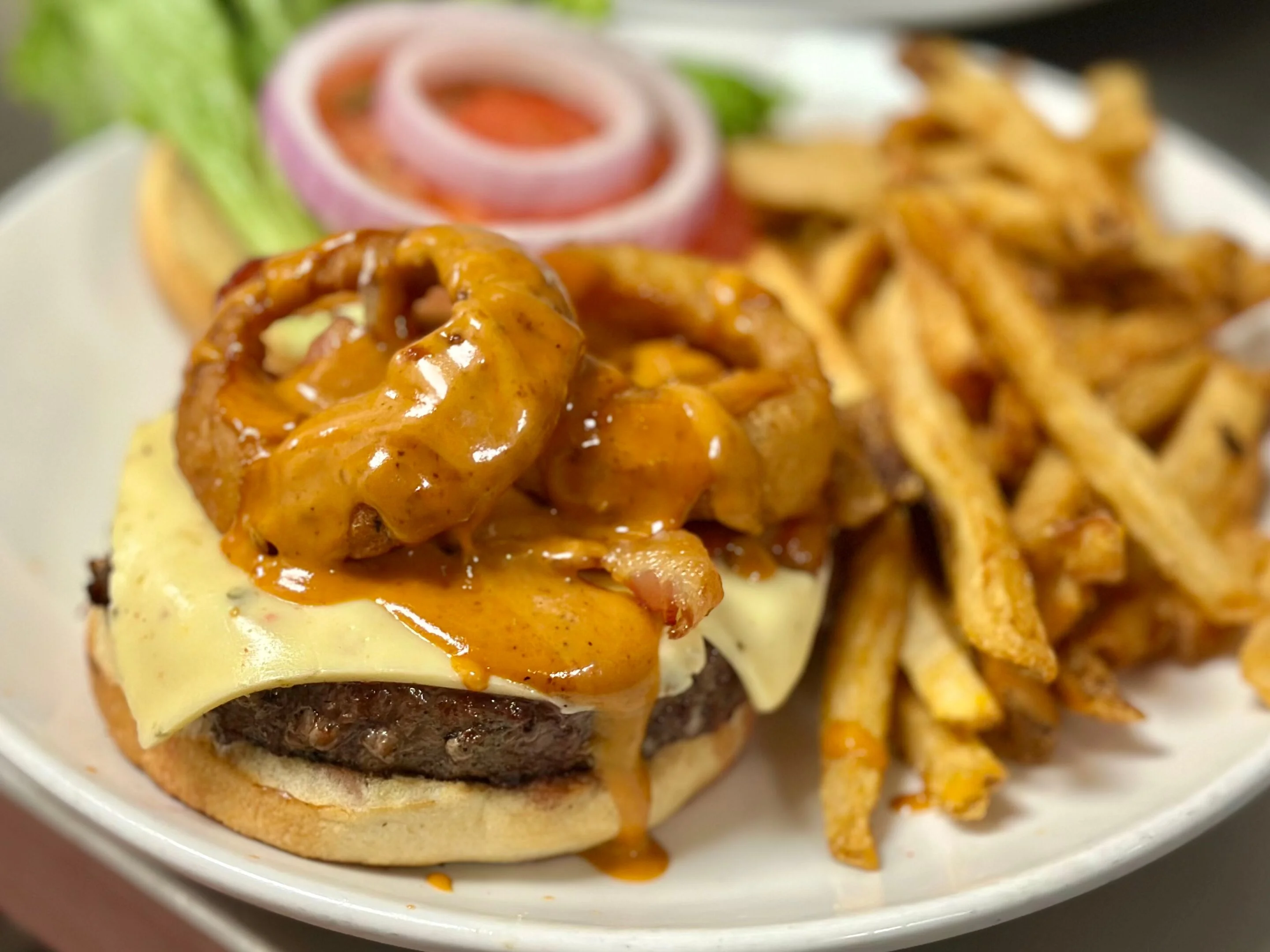 Juicy American cheeseburger with onion rings and fries