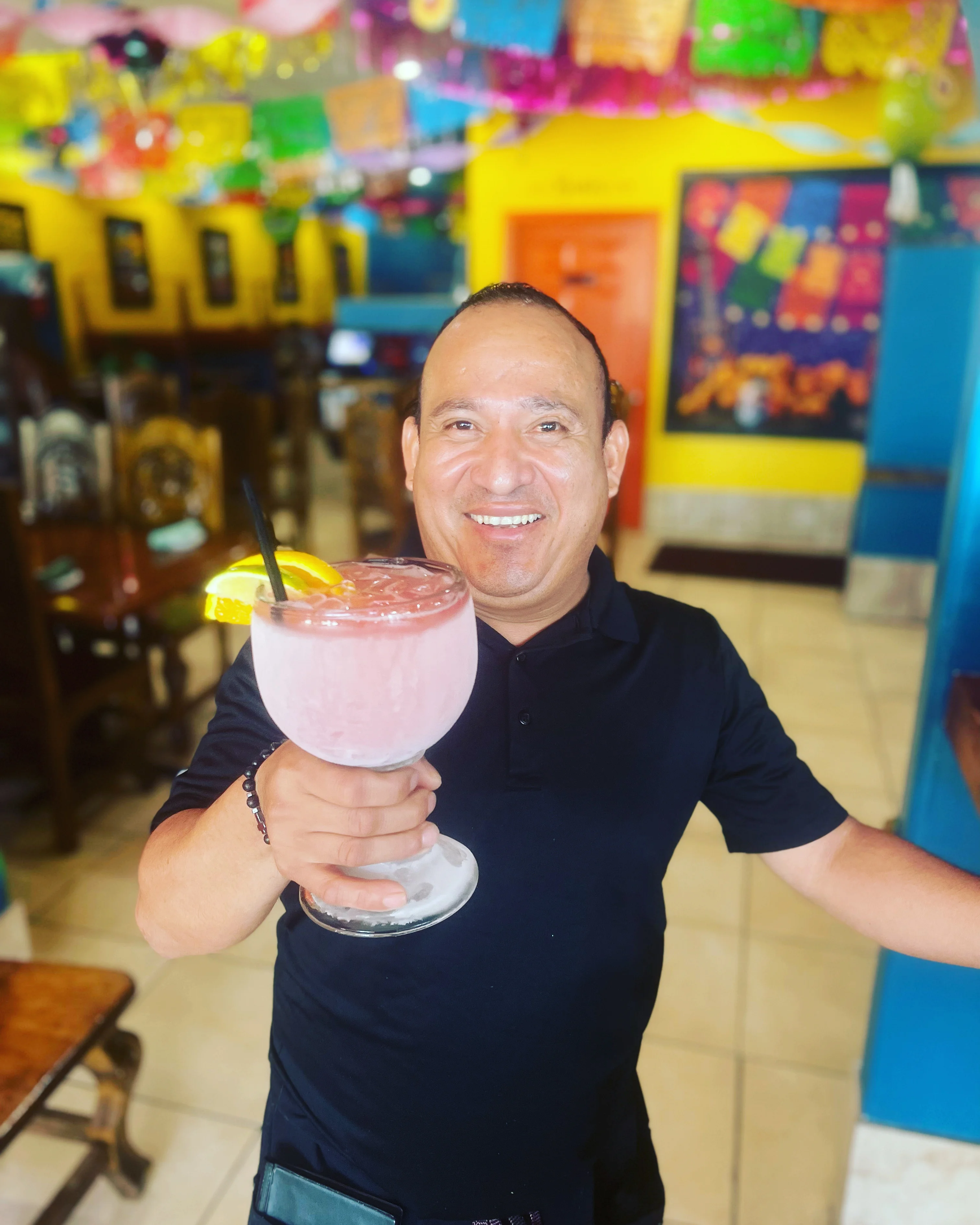 Bartender serving a vibrant cocktail in a lively restaurant setting