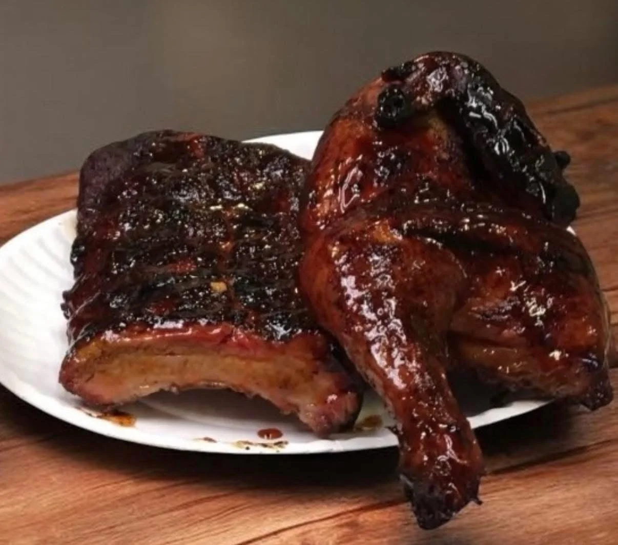 Grilled chicken and ribs glazed with barbecue sauce on a plate.
