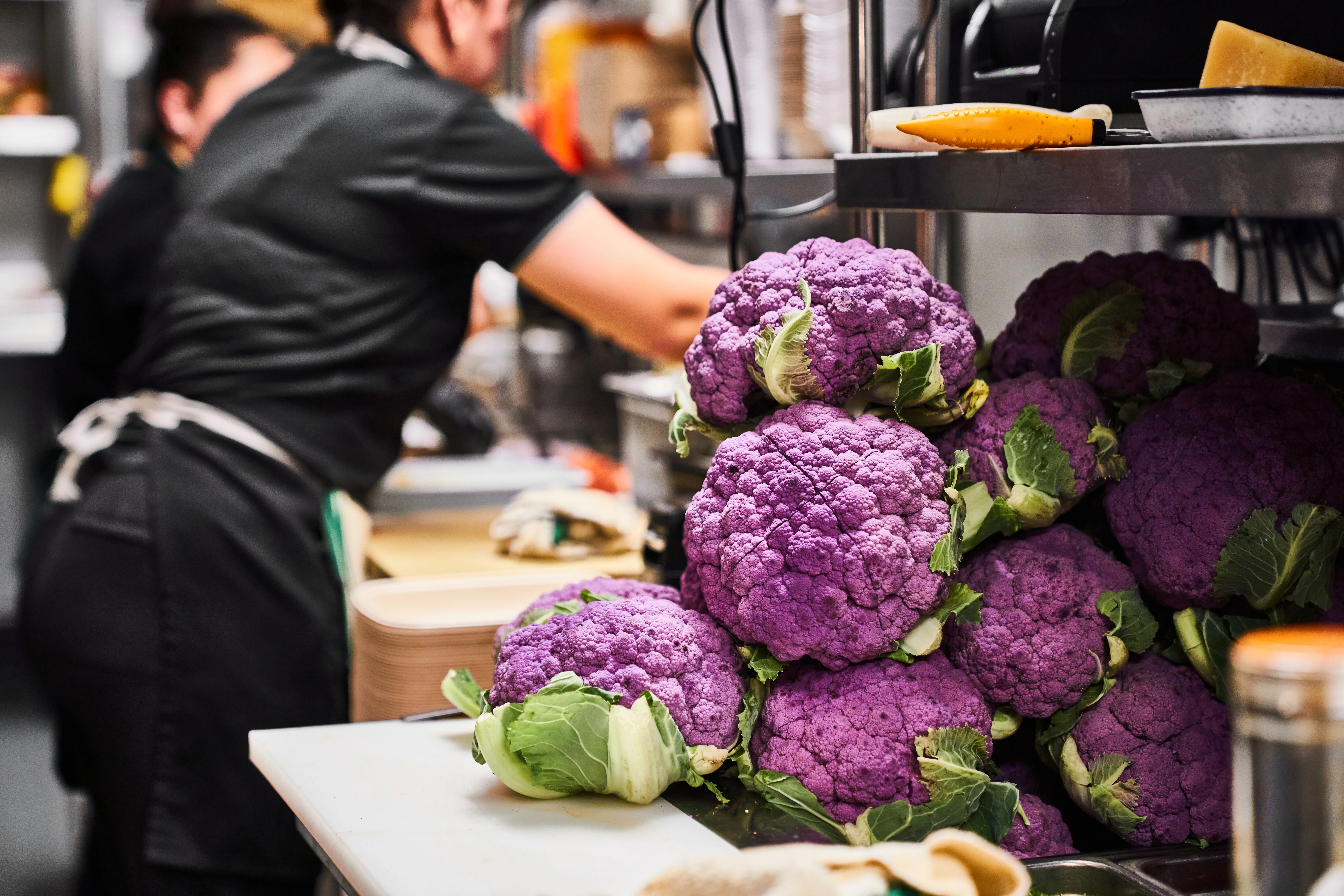 Purple Cauliflower heads on  cutting board in a commercial kitchen