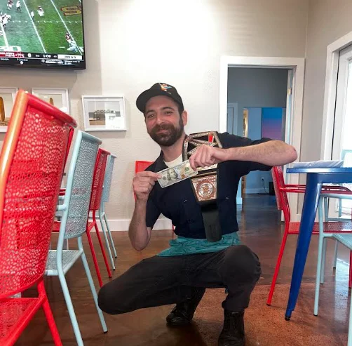 Restaurant staff posing with a championship belt and cash