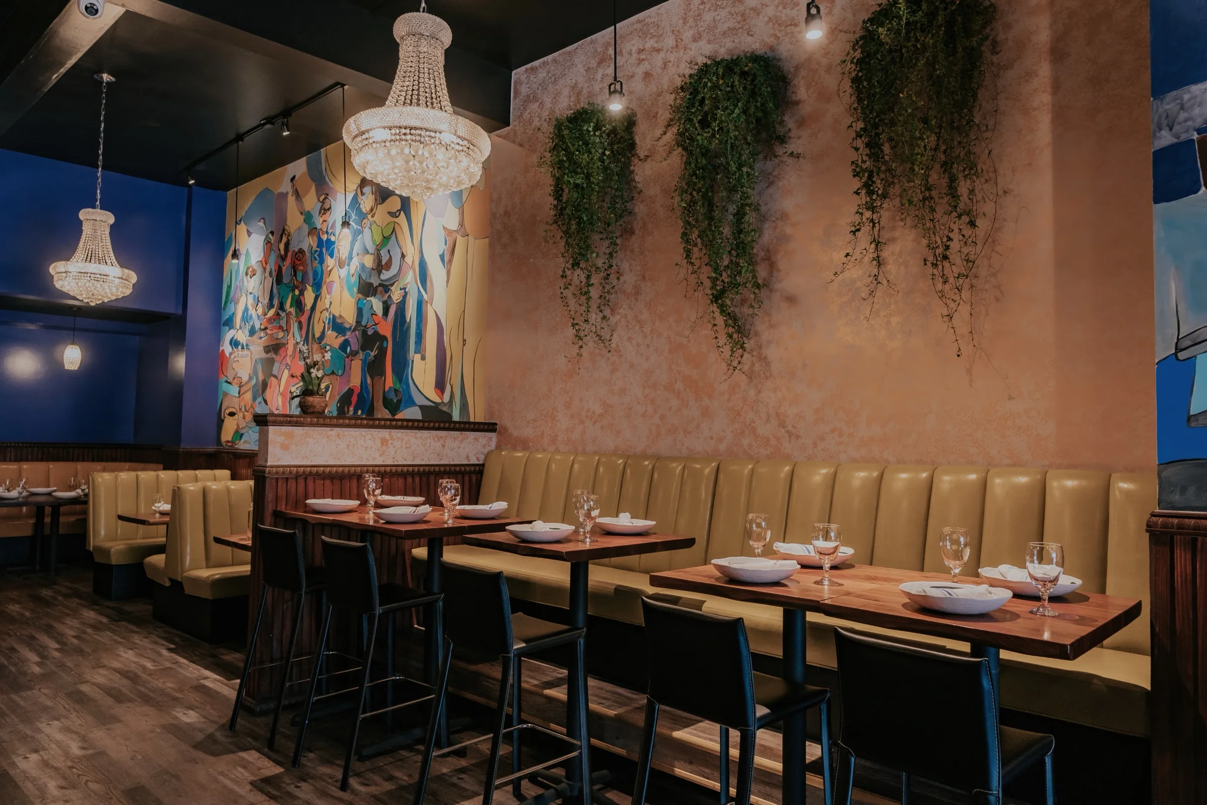 Chandeliers, colorful mural and yellow banquette seating at Castro Indian Restaurant