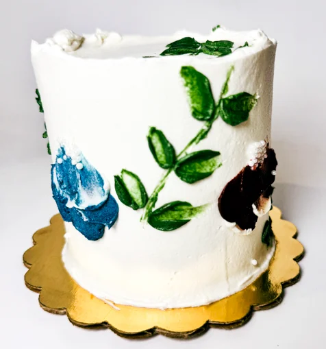 Hand-painted floral buttercream cake on a gold scalloped cake board