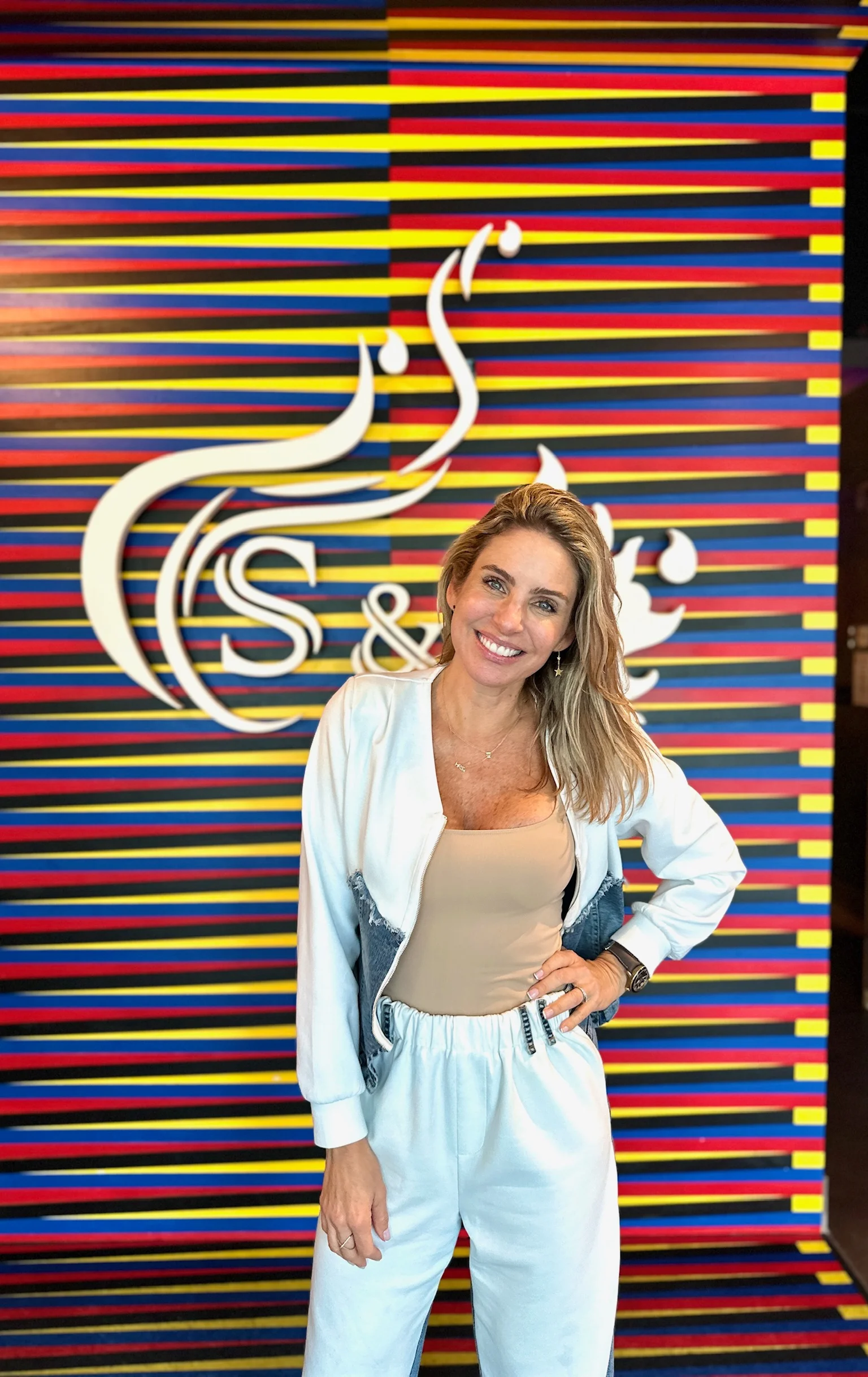 Smiling woman in stylish outfit at a vibrant restaurant backdrop