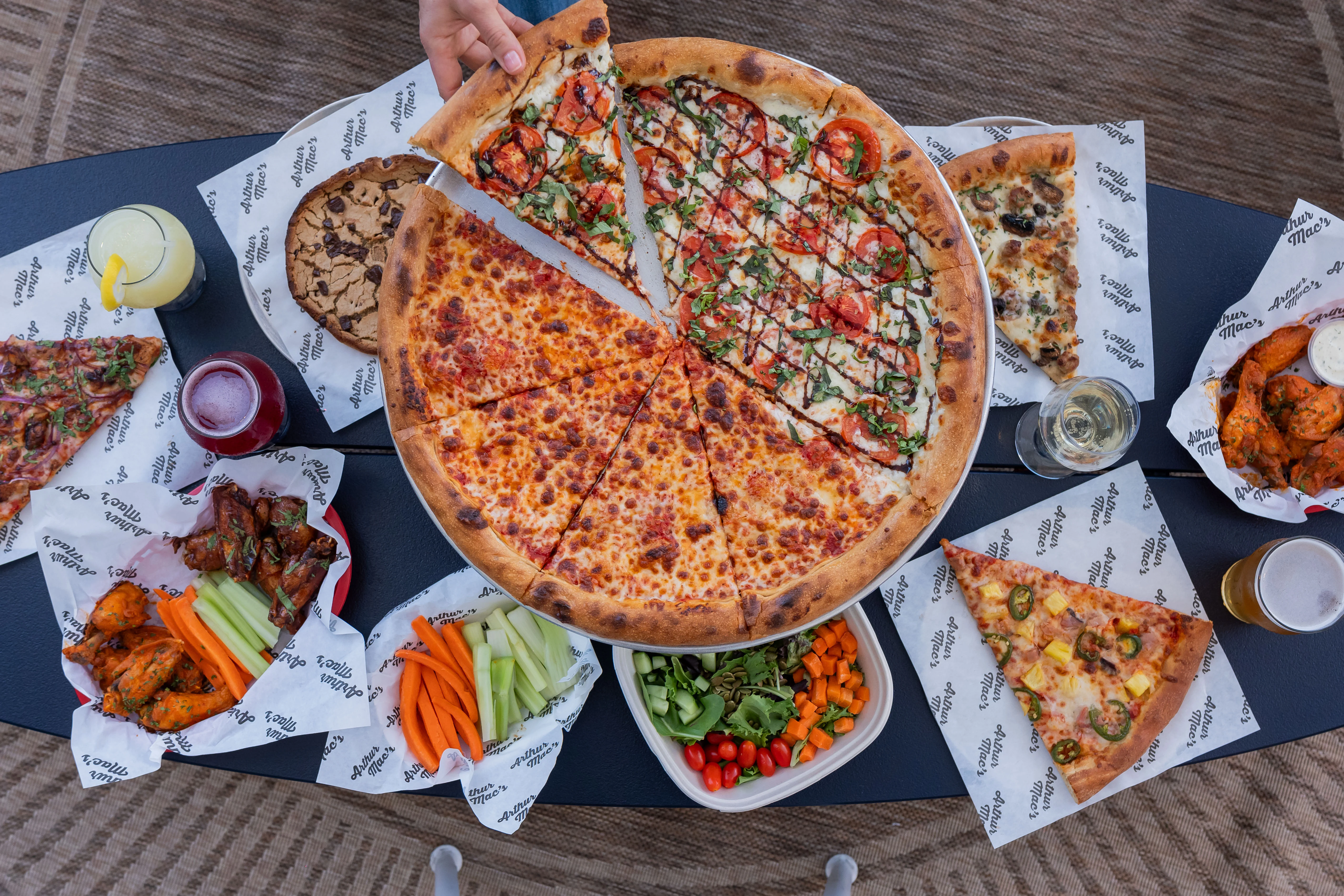 Assorted pizzas and wings on a table in a casual dining setting