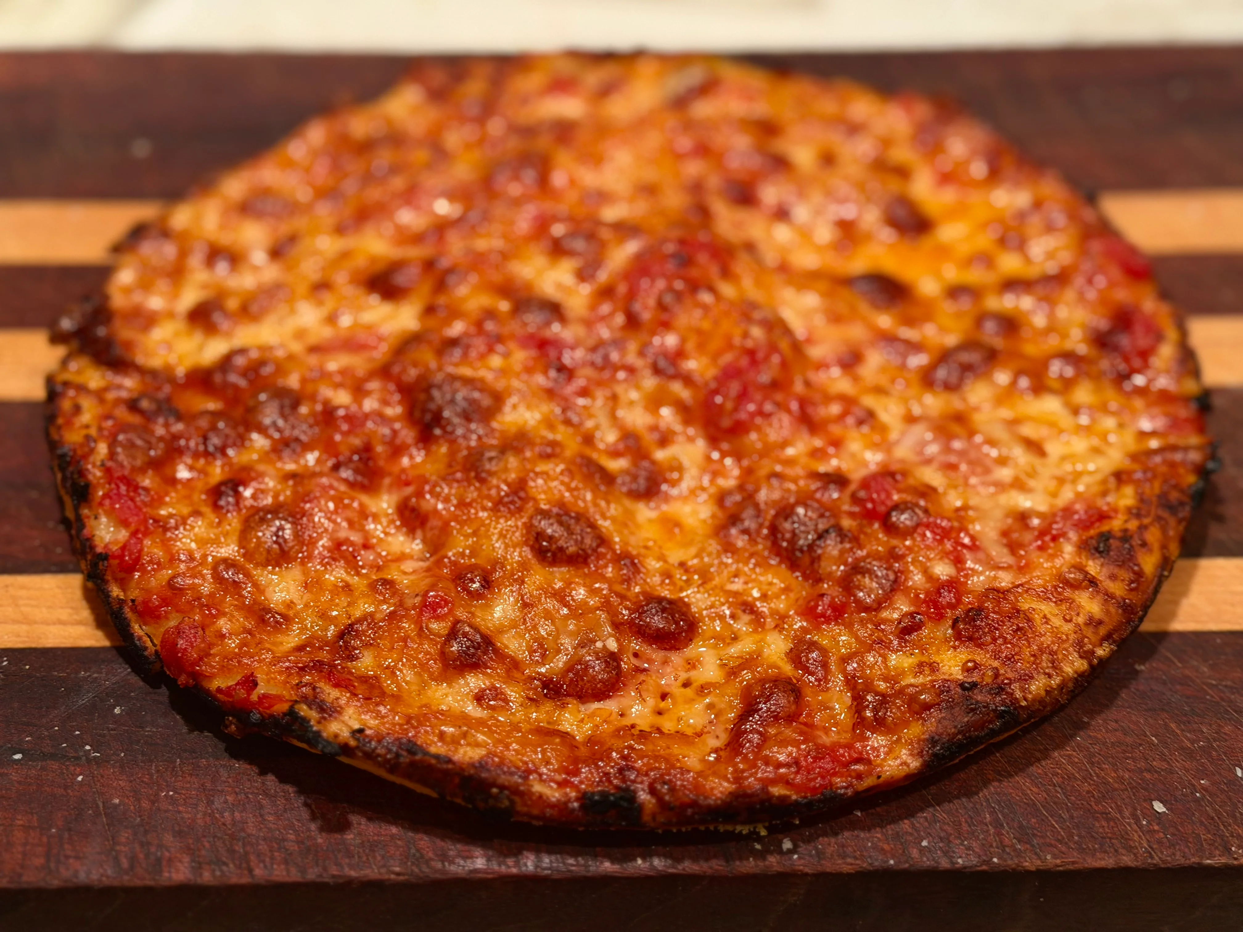 A freshly baked pizza with a golden, crispy crust and melted cheese, presented on a wooden surface.