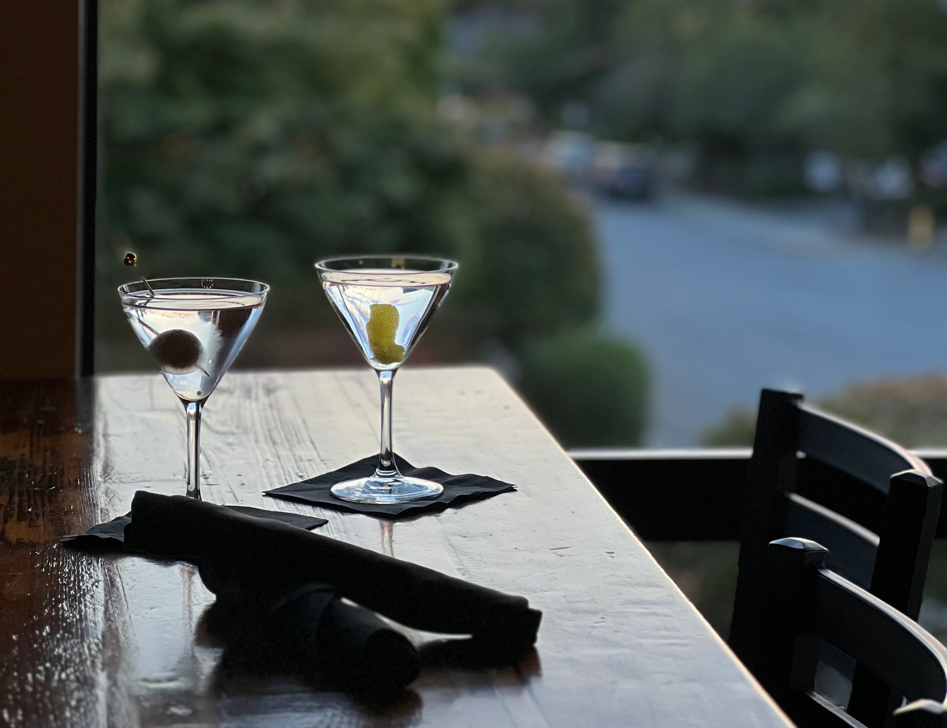Two martini glasses with a sunset view from a restaurant window