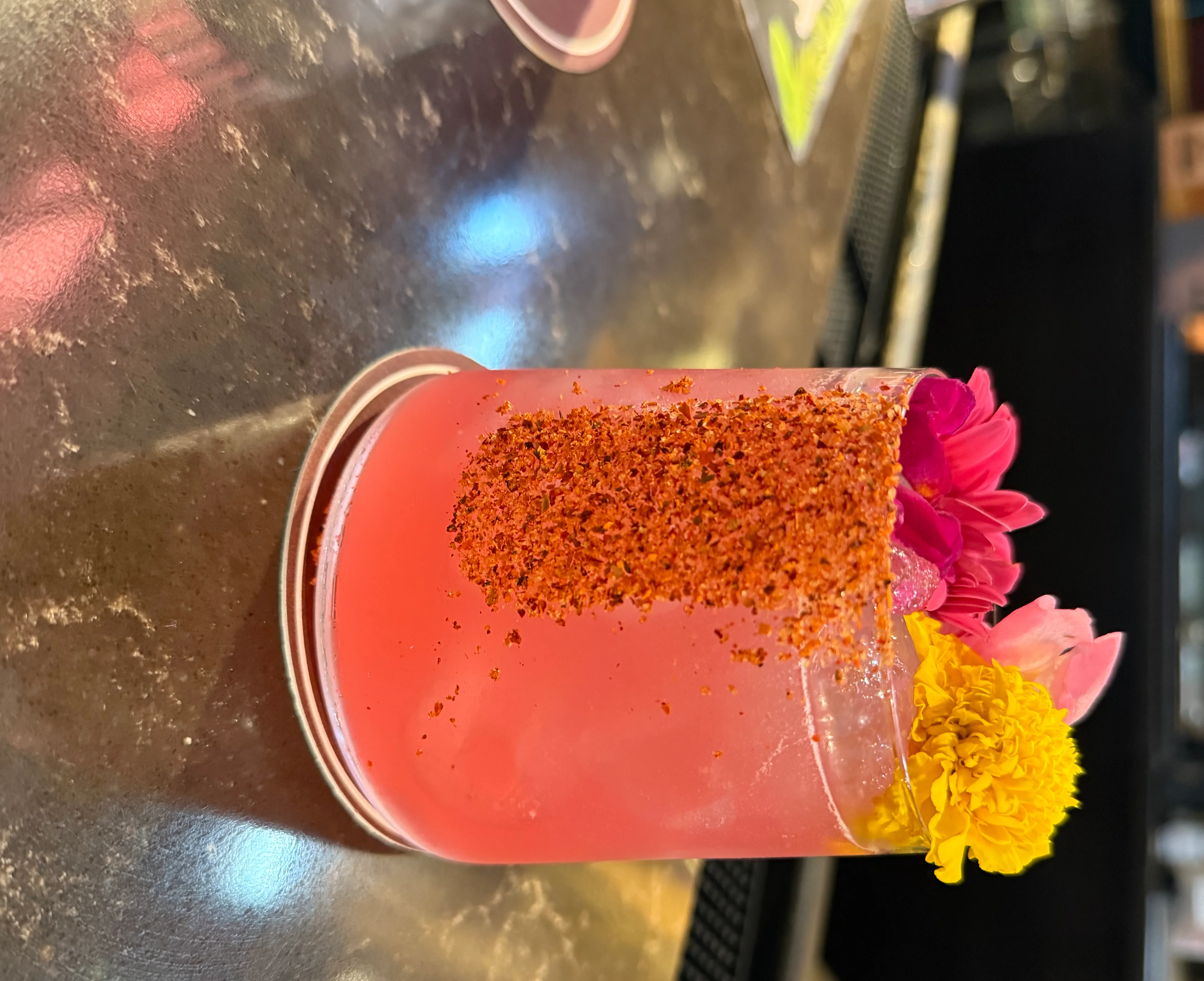 Colorful cocktail garnished with flowers and chili salt