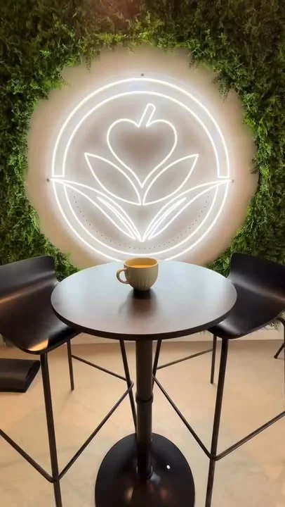 A graphic logo featuring a heart-shaped design above two stylized leaves, set against a bright yellow background.