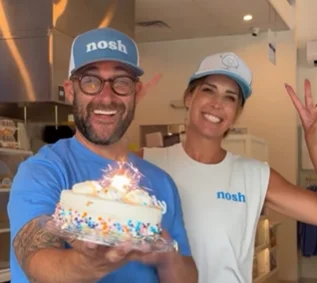 nosh NY Bagels owners celebrating the grand opening of their new Hilton Head Island location with an authentic New York bagel bakery cake.
