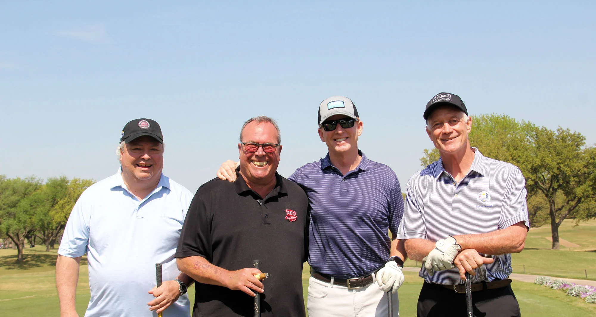 Four golfers posing together on a sunny golf course
