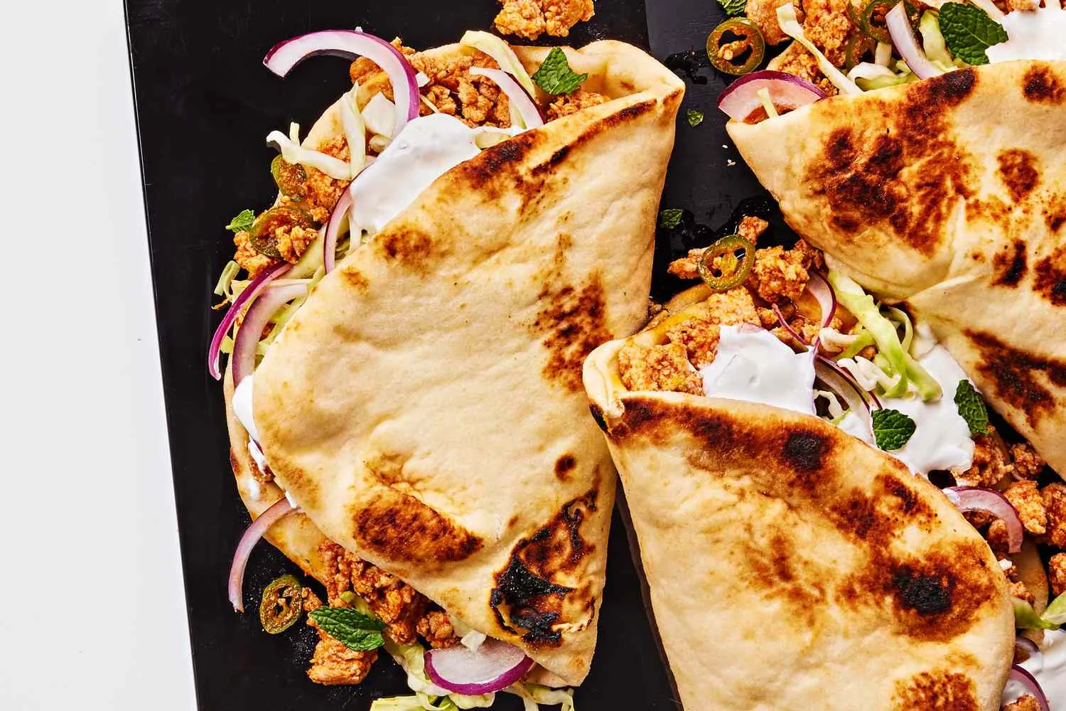 Fresh naan wraps filled with Indian-spiced chicken, Masala rice, greens, and pickled onions at Infinity Indian Eats in Medford