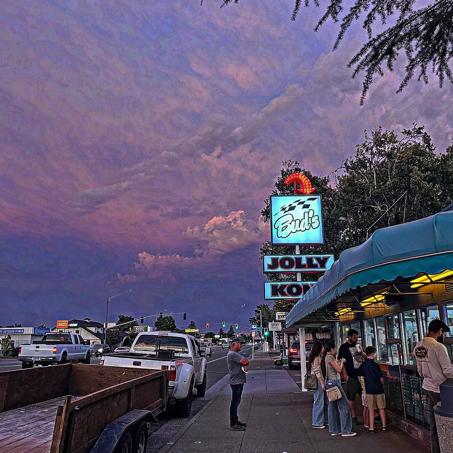 Vibrant sunset over a bustling street with diners at a local eatery