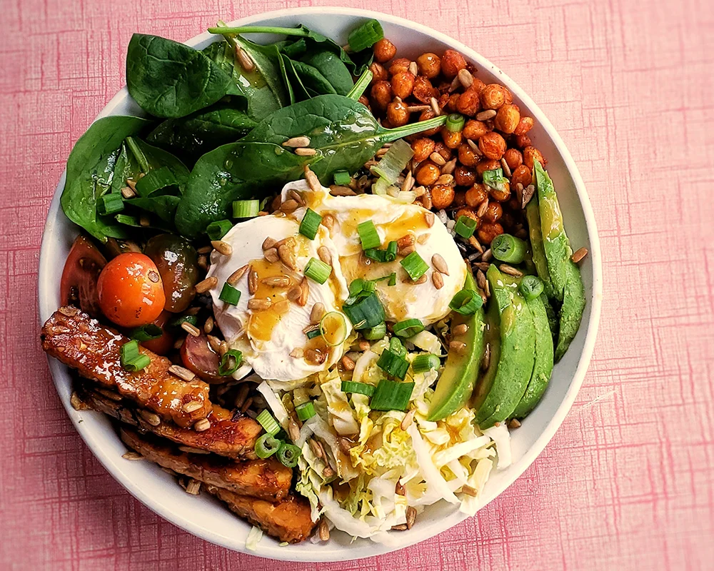 Colorful grain bowl with poached egg and fresh vegetables