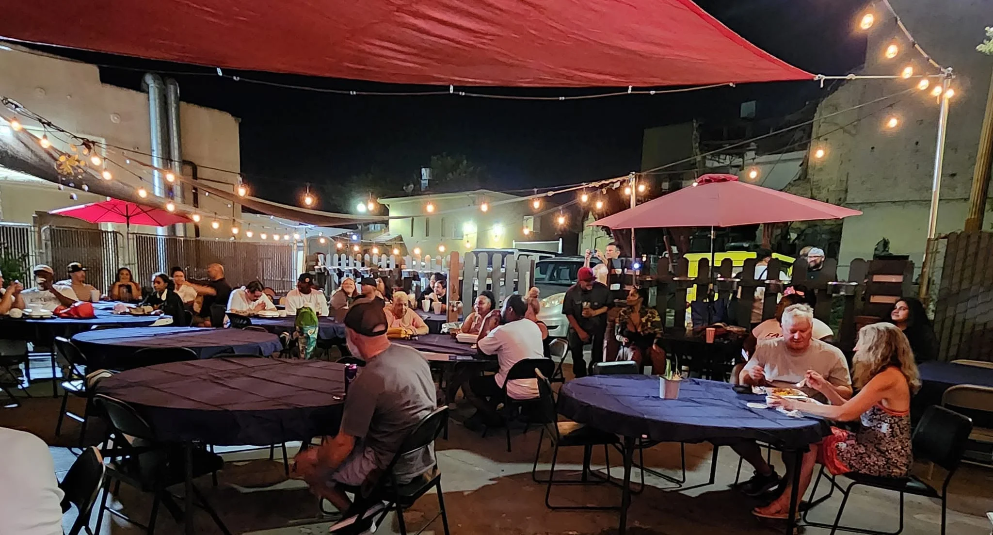 Outdoor dining area with guests enjoying a lively evening atmosphere