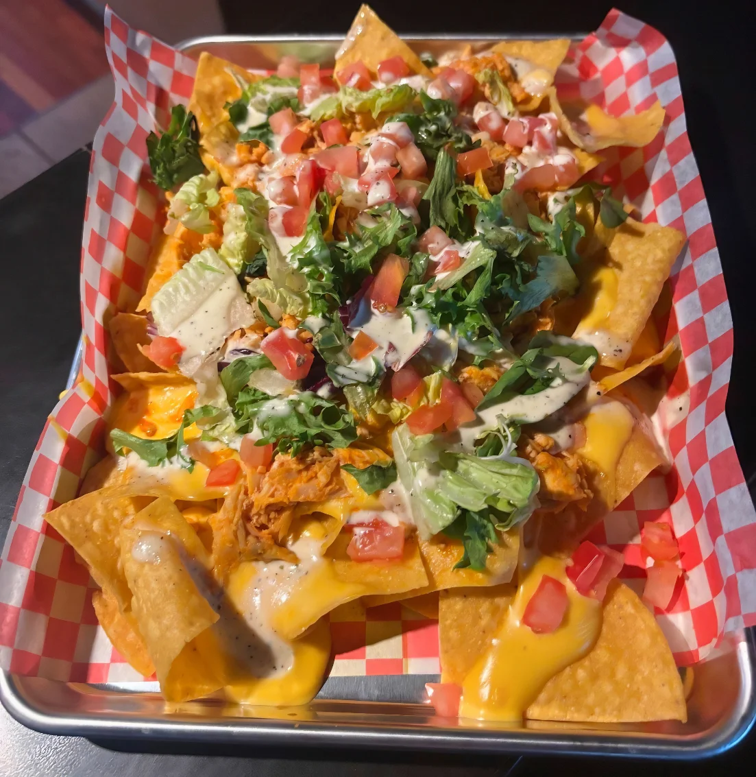 Loaded nachos topped with fresh vegetables and creamy sauce