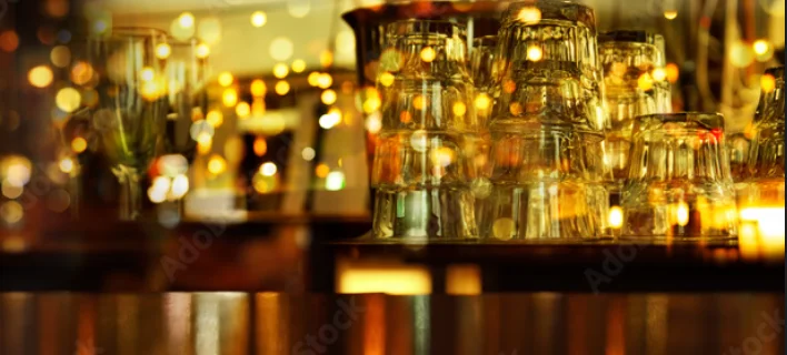 Warmly lit bar with stacked glassware and bokeh lights
