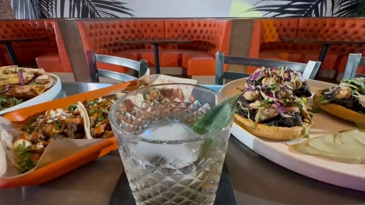Colorful Mexican tacos and tortas with a refreshing cocktail in a vibrant restaurant setting.